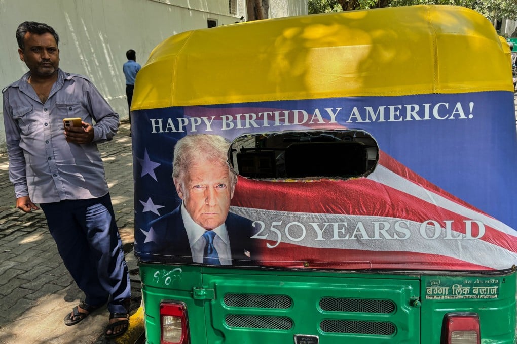 Pradeep Kumar stands next to his autorickshaw featuring a poster of US President Donald Trump in New Delhi on Wednesday. Photo: AP