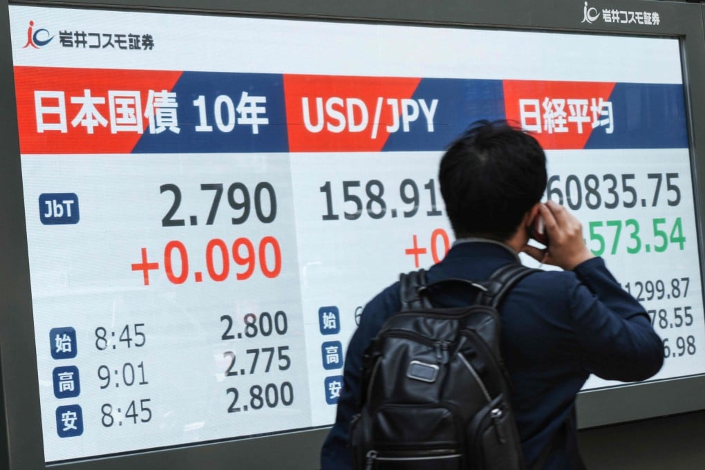 A man walks past an electronic board displaying 10-year Japanese government bonds, an index of long-term interest rates in the Tokyo bond market and the foreign exchange rate of the Japanese yen against the US dollar along a street in Tokyo on May 18. Photo: AFP