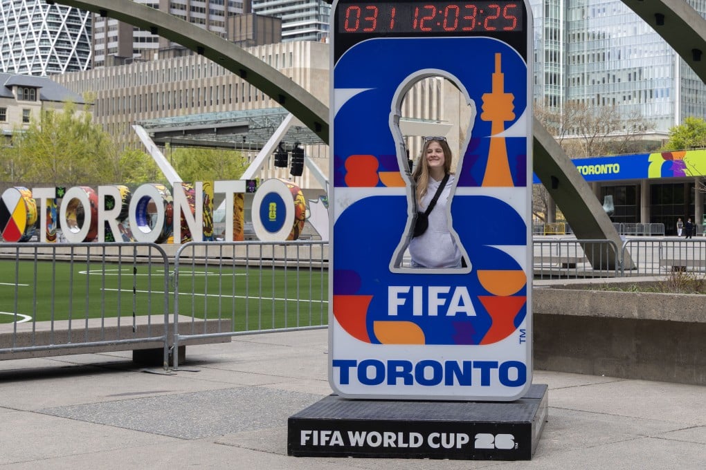 A visitor poses for a photograph with the official Fifa World Cup 2026 Toronto countdown clock at Nathan Phillips Square in Toronto, Canada, on May 11. Photo: Xinhua