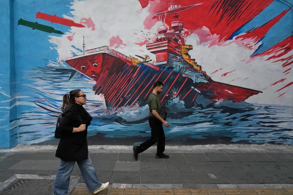 Pedestrians in downtown Tehran walk past a mural depicting a US aircraft carrier under missile attack. Photo: AP