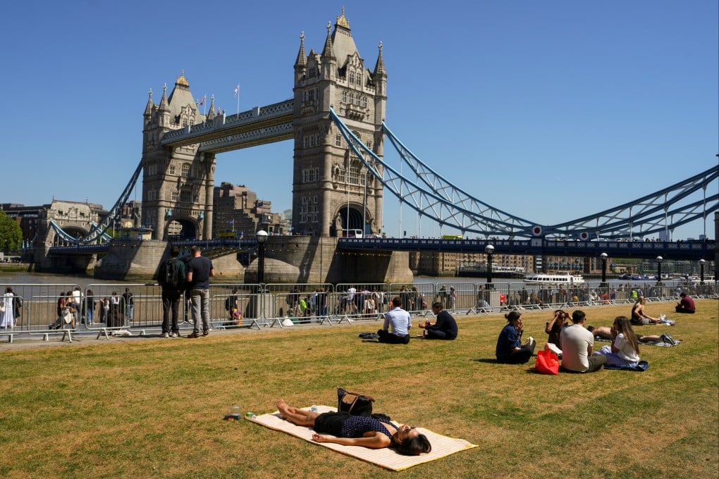 Londoners bask in the sunshine near the British capital’s Tower Bridge. Photo: AP