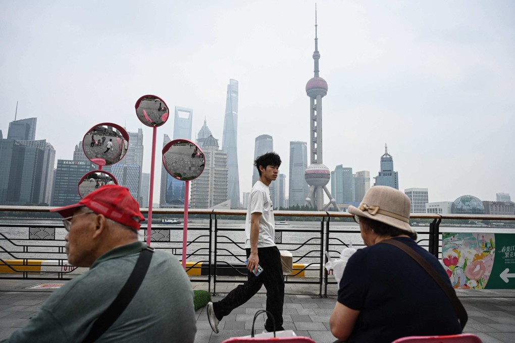 A young man walks past two elderly people resting on Shanghai’s Bund promenade on Thursday. Photo: AFP
