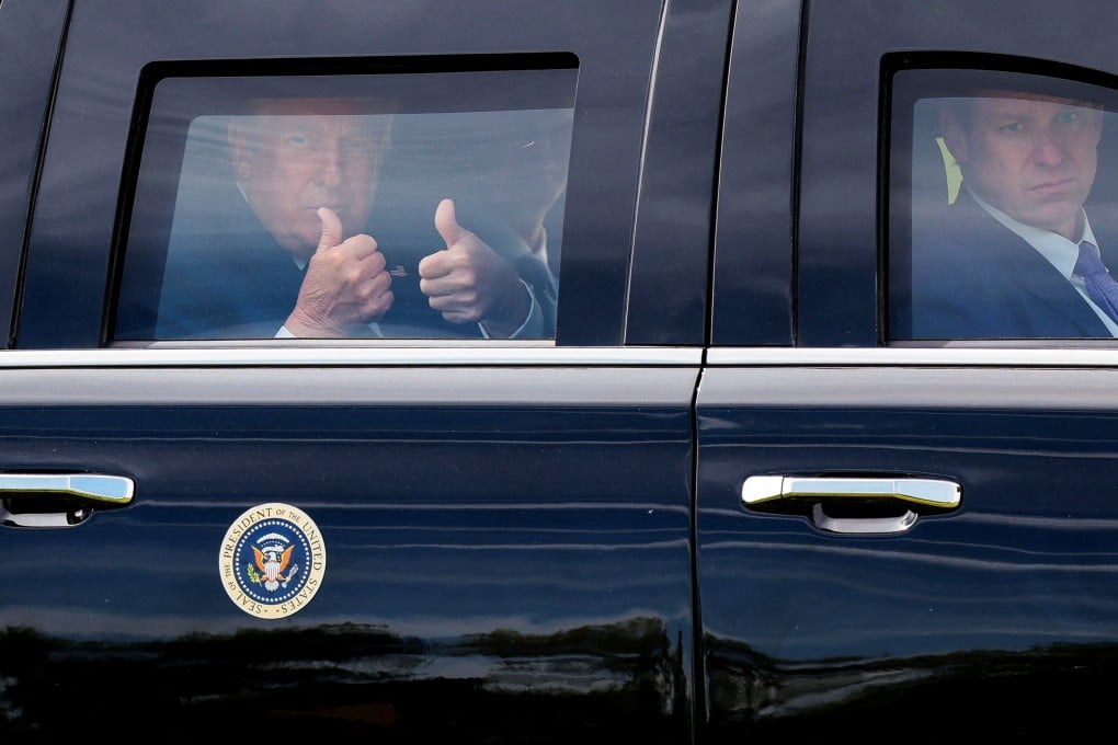 US President Donald Trump gives a double thumbs-up from inside his limousine. Photo: Reuters