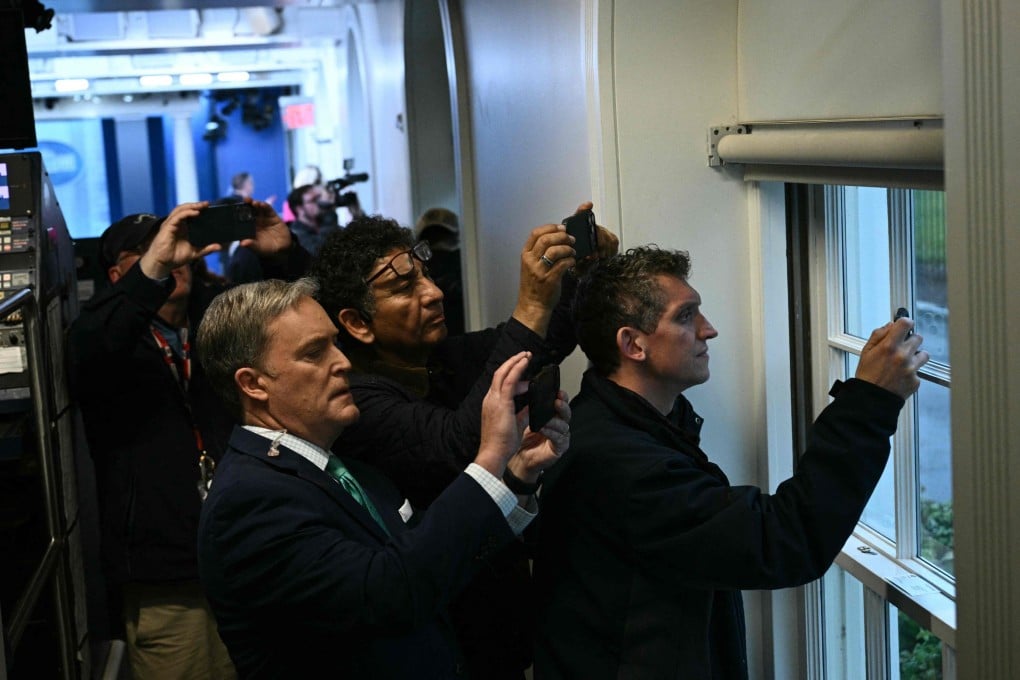 Reporters hold up their phones near a window in the Press Briefing room after a lockdown is triggered by a shooting near  the White House on Saturday. Photo: AFP