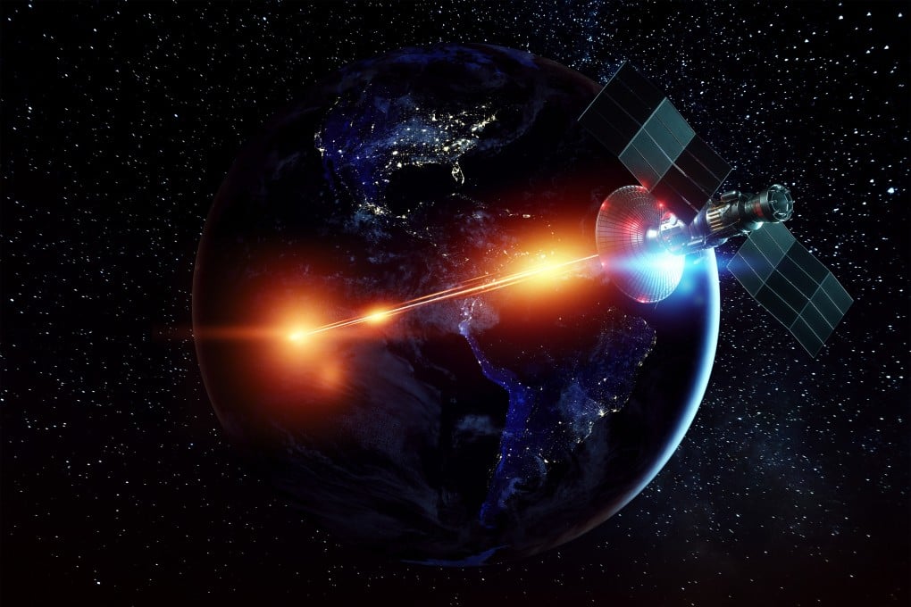 An illustration shows a space military satellite shooting a laser against the background of the Earth. Photo: Shutterstock