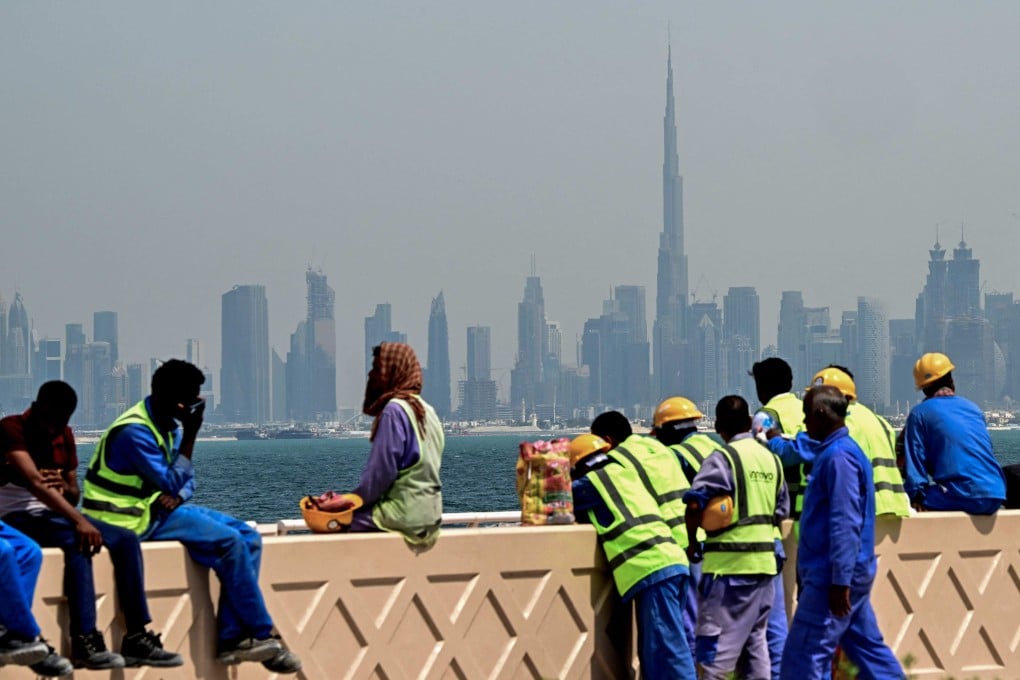 Workers take a break with the city skyline of Dubai seen in the background on March 11. Photo: AFP