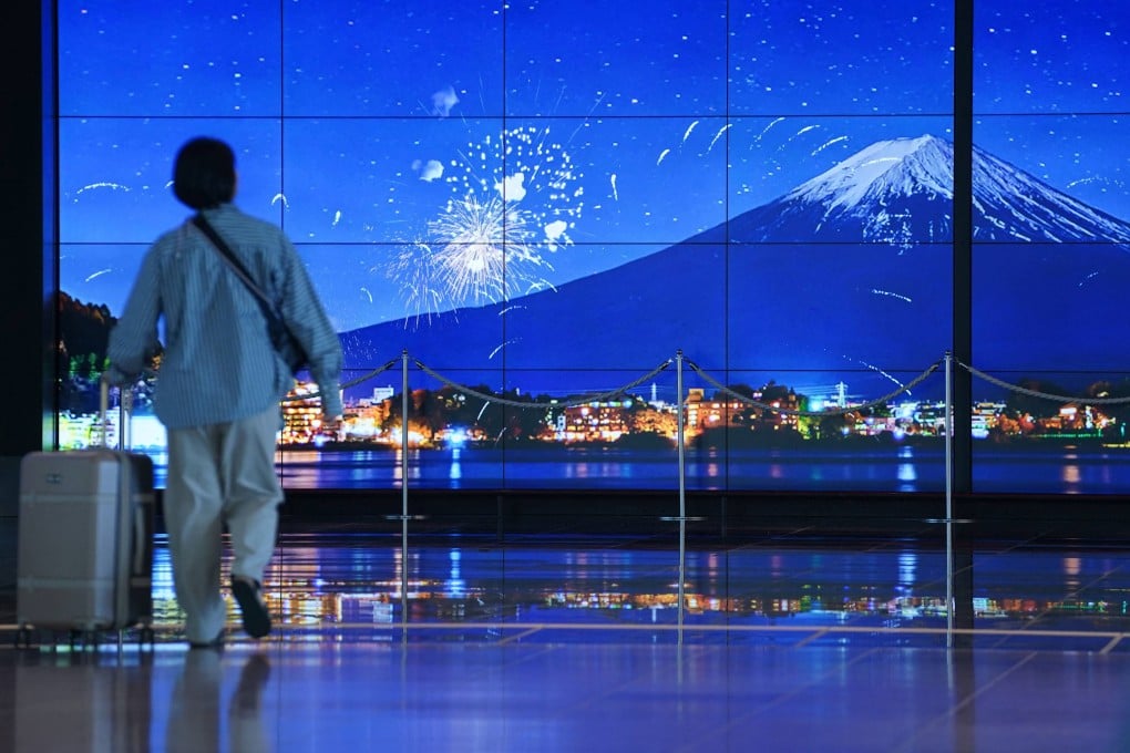 A traveller walks past an image of Mount Fuji in the arrivals terminal at Haneda Airport in Tokyo on May 20. Photo: AFP
