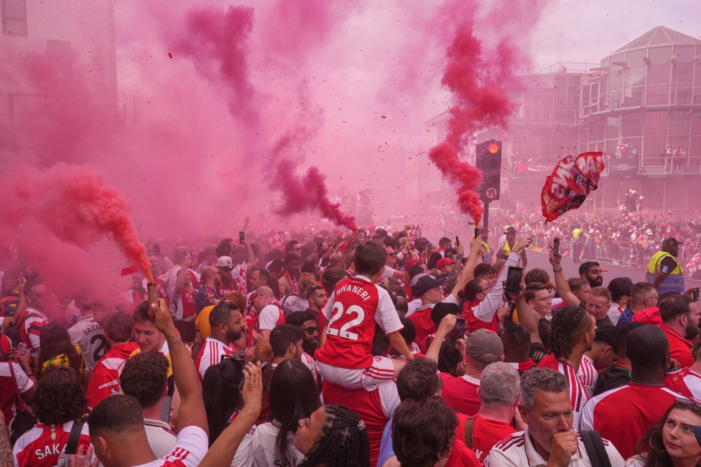 Arsenal fans fire off flares and wave flags as they wait for the bus carrying the team in London on Sunday. Photo: AP