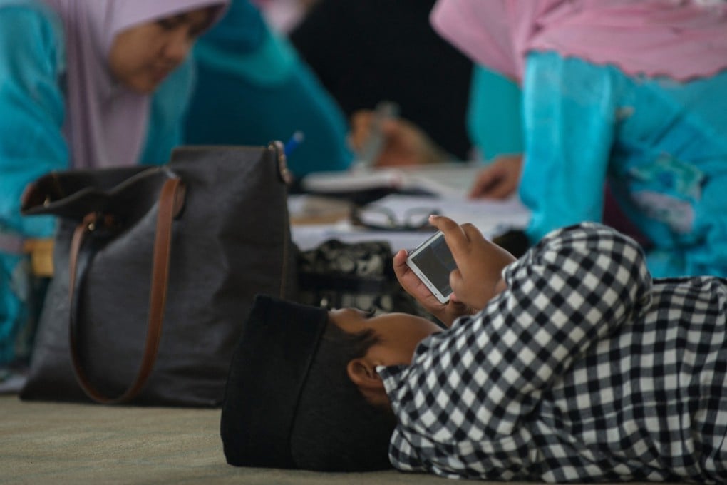 A young boy plays with a phone inside a mosque in Putrajaya, Malaysia. Photo: AFP