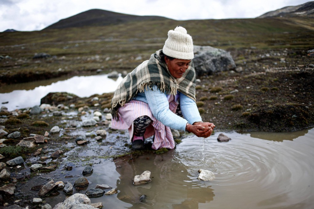 An Andean woman washes her hands in a nearly dried-up lake in central Peru in November 2023, amid an El Nino-linked drought. Photo: AFP