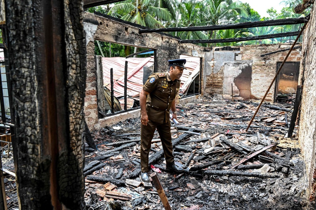 A police personnel inspects the burnt house on Thursday, a day after a fire broke out at an elder care home in Sri Lanka’s Batagoda. Photo: AFP
