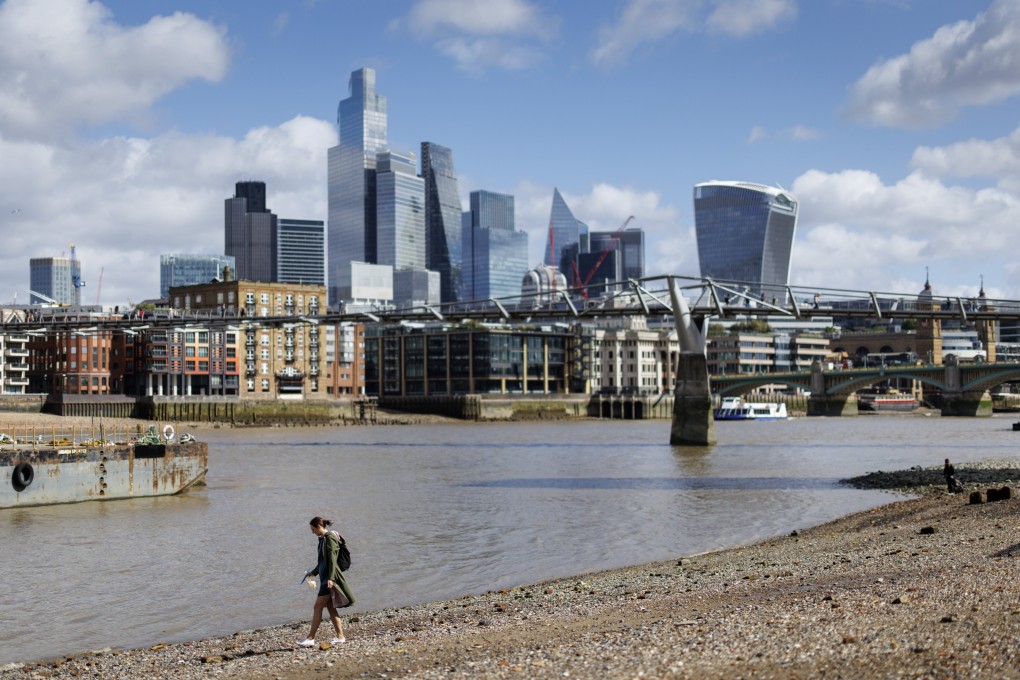 A pedestrian walks along the River Thames and mudlarks during low tide, with the City of London financial district in the background on September 15, 2025. Photo:  EPA