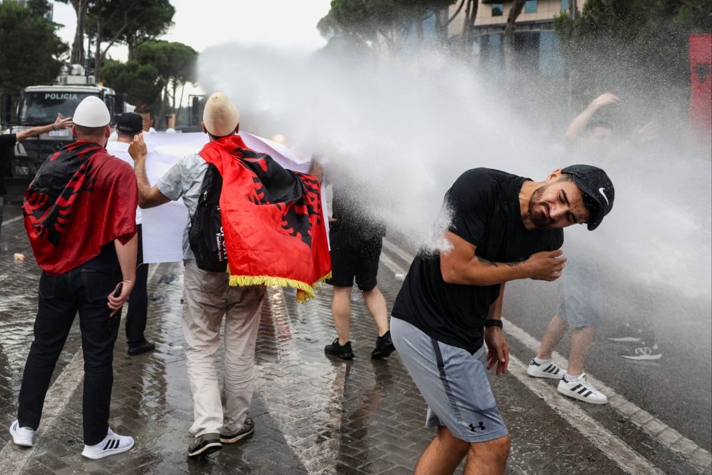 A demonstrator is hit with a water cannon used by police during a protest in Tirana, Albania, against the luxury resort. Photo: Reuters