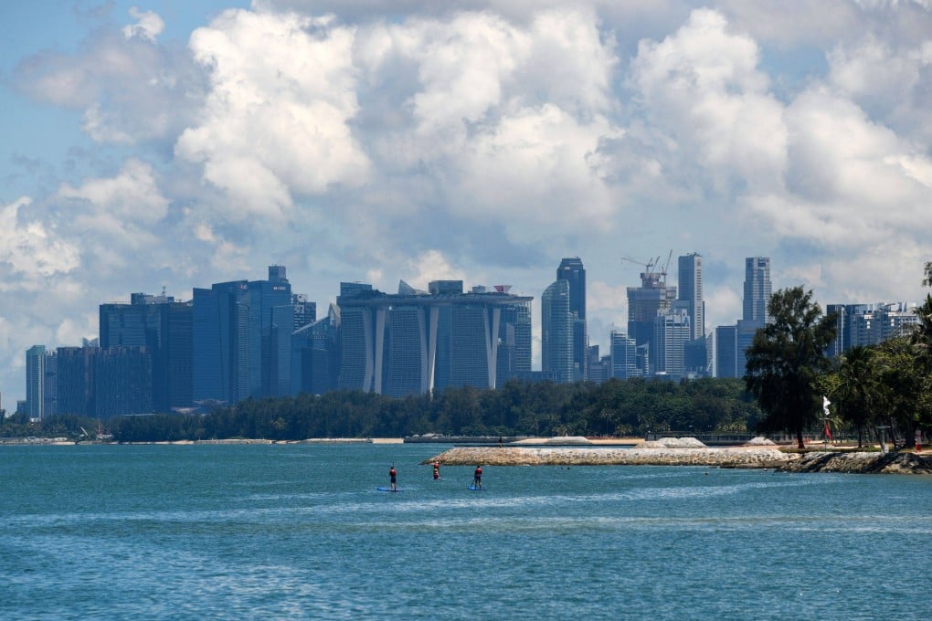 Singapore’s skyline is seen in the background as people paddleboard in the sea off East Coast Park. Photo: AFP