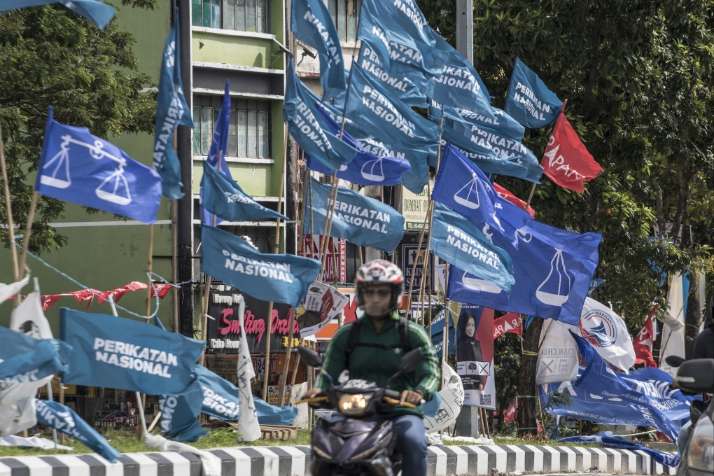 A motorcycle passes campaign flags of Malaysia’s Barisan Nasional (blue) and Pakatan Harapan (red) coalitions displayed in Kuala Lumpur in 2022. Photo: AP
