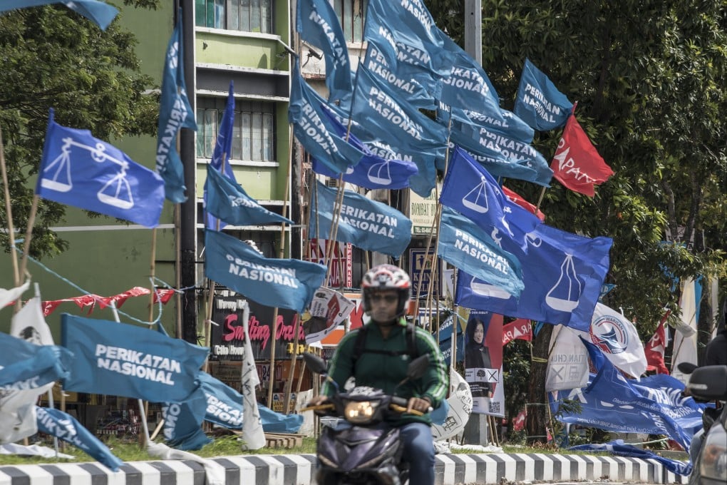 A motorcycle passes campaign flags of Malaysia’s Barisan Nasional (blue) and Pakatan Harapan (red) coalitions displayed in Kuala Lumpur in 2022. Photo: AP