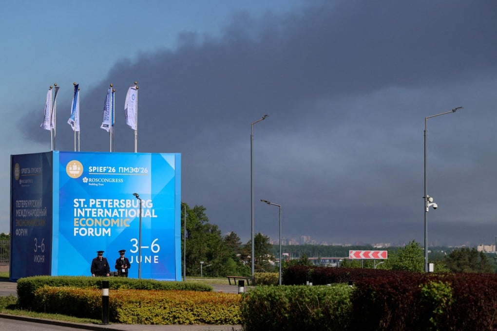 Police officers stand in front of a banner and flags with the logo of the Saint Petersburg International Economic Forum as heavy smoke billows in the background after Ukrainian drones hit infrastructure on Wednesday. Photo: Reuters