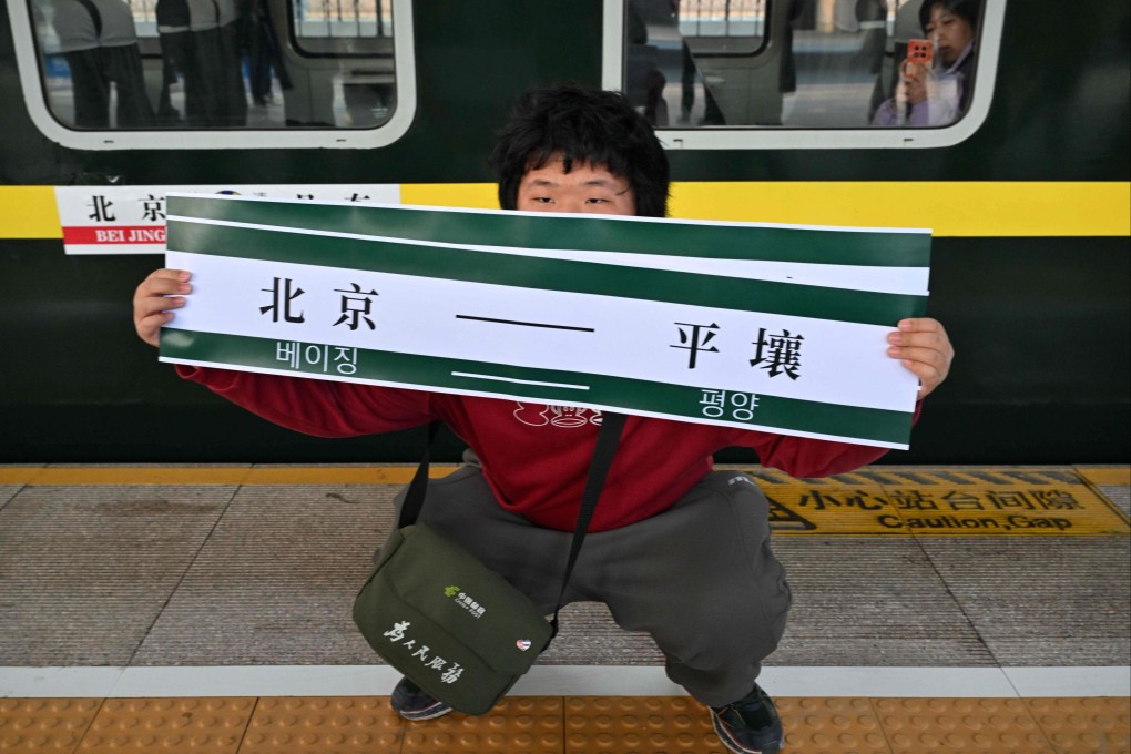 A man holds a banner reading “Beijing – Pyongyang” in front of the K27 train bound for Pyongyang at Beijing Railway Station on March 12. The first passenger train service from North Korea to China crossed the border that day for the first time in six years. Photo: AFP