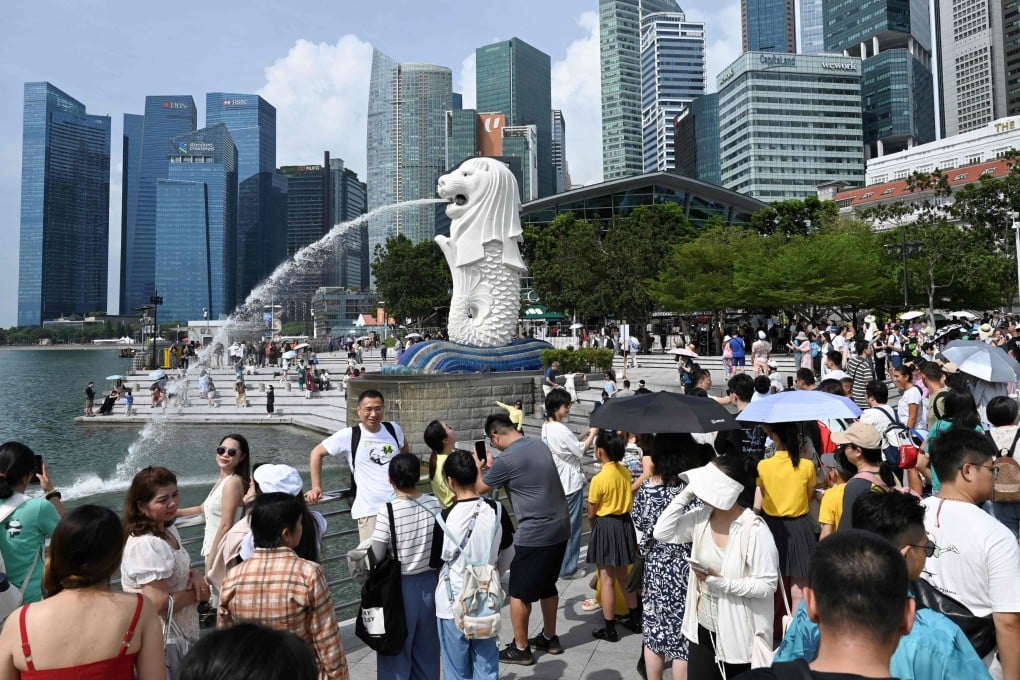 People stand next to the Merlion statue at the Marina Bay Waterfront Promenade in Singapore. Photo: AFP
