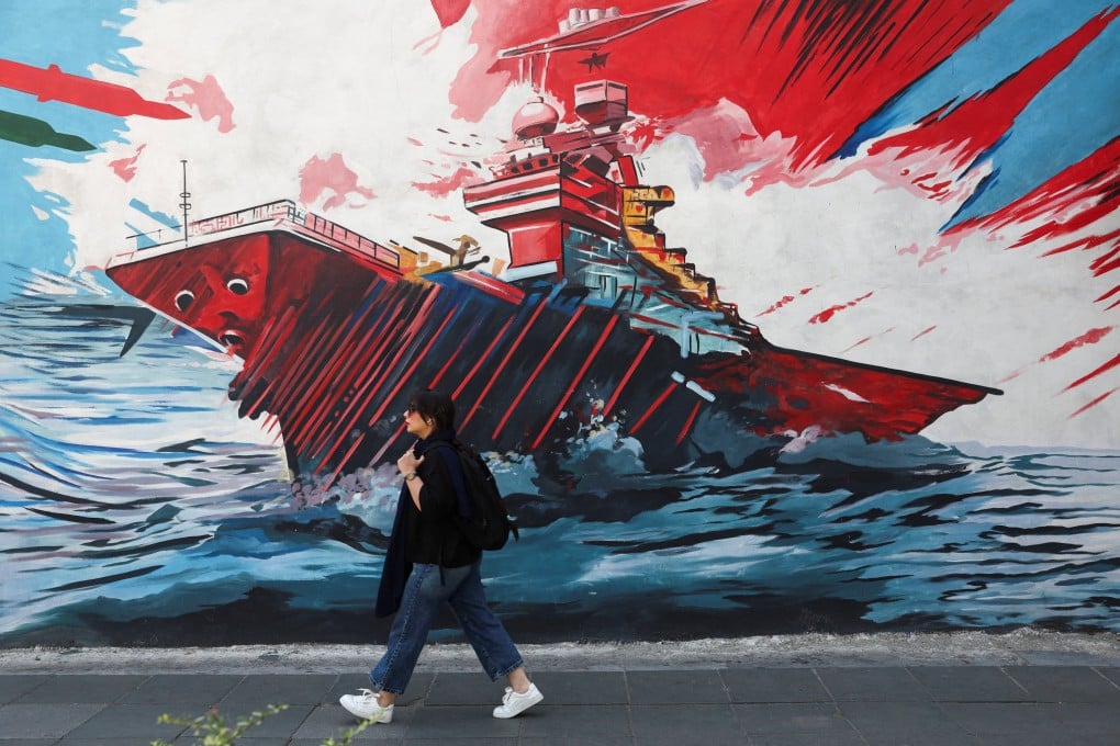 An Iranian woman walks next to an anti-US mural on a street in Tehran on Wednesday. Photo: West Asia News Agency via Reuters