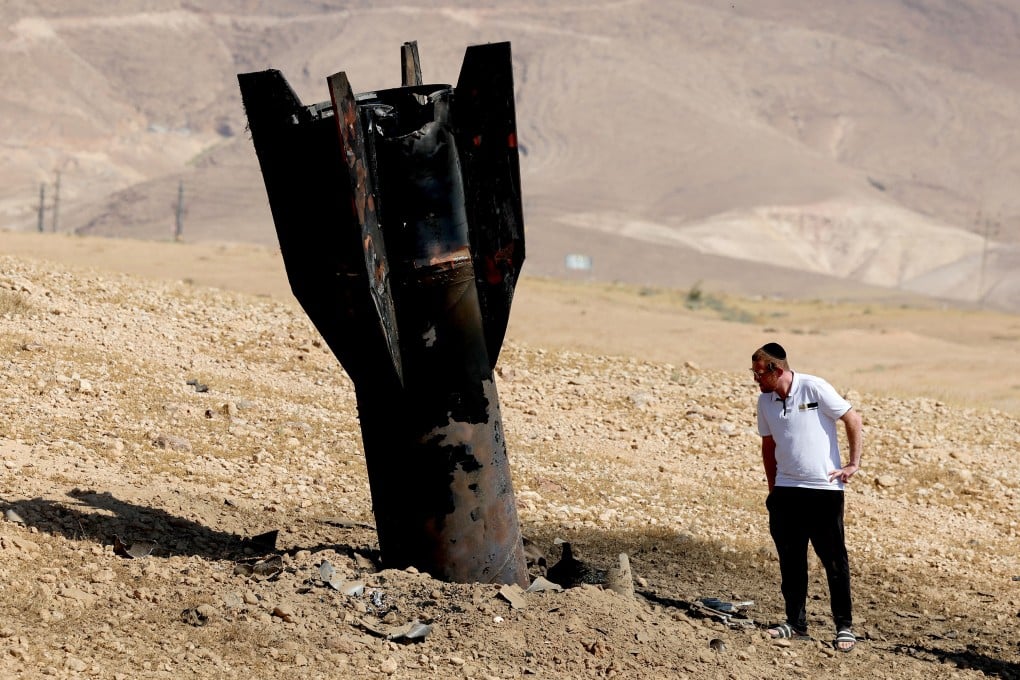 A man checks a fallen rocket half-buried in the ground on the outskirts of Jericho on Monday, following Iranian and Iran-backed Houthi rebel attacks. Photo: TNS