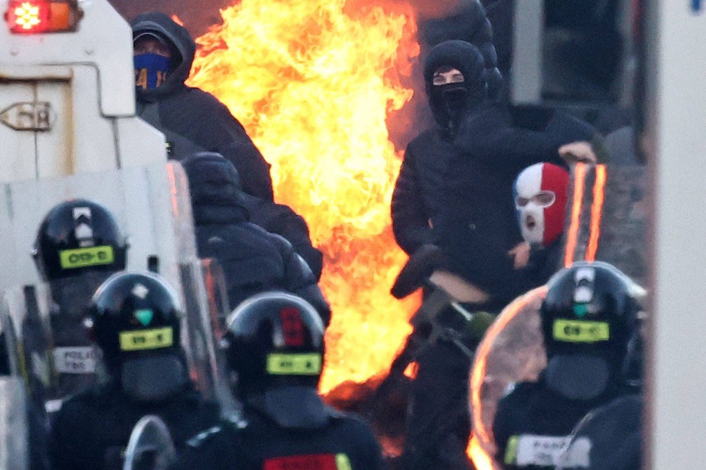 Masked rioters clash with police blocking their way to a hotel housing asylum seekers in Glengormley, north of Belfast, on Wednesday night. Photo: AFP