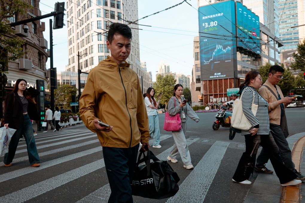 People walk beneath a large screen showing the latest stock exchange and economic data in Shanghai last month. Photo: EPA