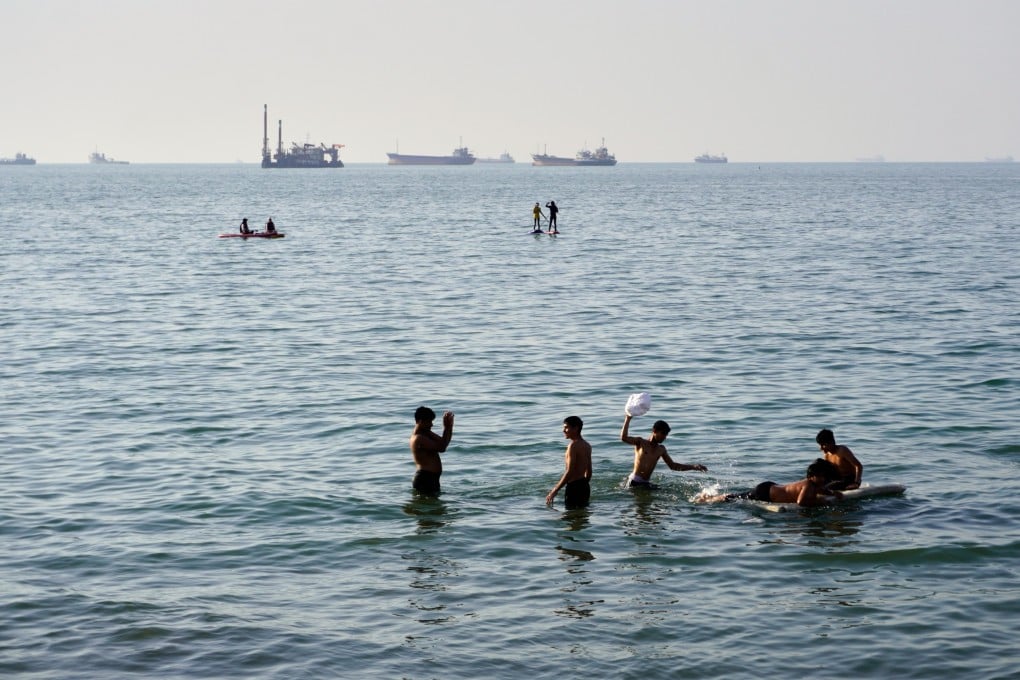Residents swim and play in the waters of the Strait of Hormuz while ships lie anchored in the distance off Bandar Abbas, Iran, on Wednesday. Photo: ISNA via AP