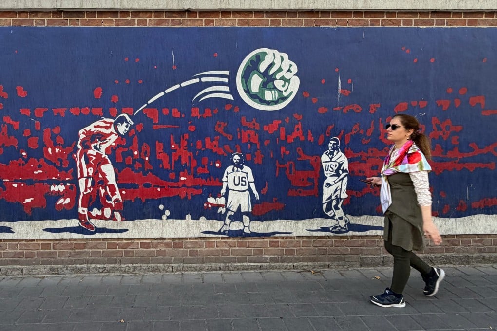 A woman walks past a mural in Tehran on Friday depicting Iranian midfielder Hamid Estili scoring against the US States during their 1998 Fifa World Cup match. Photo: AP