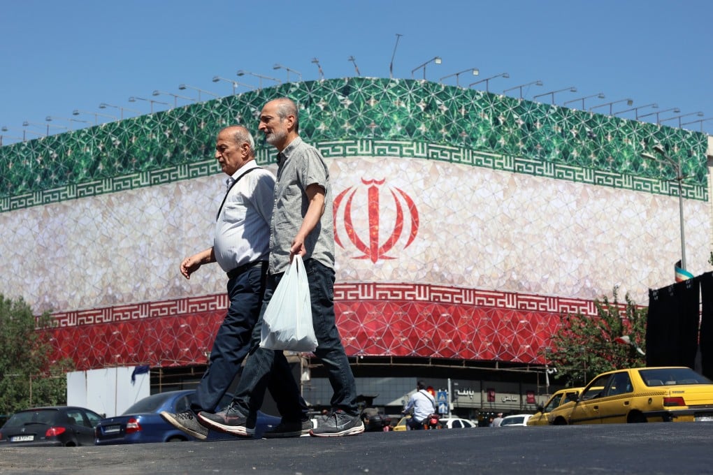 Iranians walk past a billboard featuring Iran’s national flag at Enqelab Square in Tehran, Iran on Sunday as US President Donald Trump said a peace deal could be signed soon. Photo: EPA