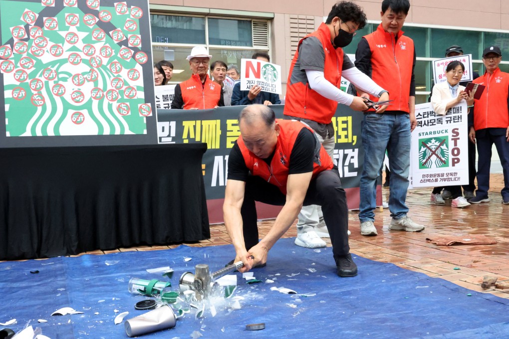An activist smashes Starbucks tumblers and mugs during a protest against its “Tank Day” campaign on May 21. Photo: Yonhap/Reuters