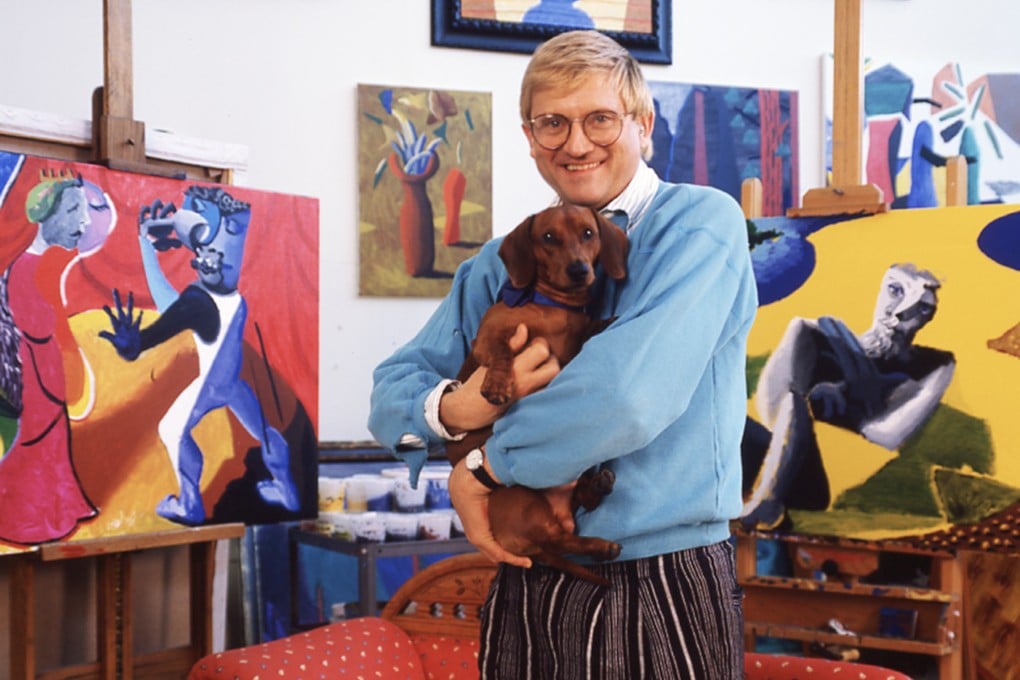 British artist David Hockney, with one of his dogs in his arms, at home in Los Angeles, California, in 1987. Photo: Getty Images