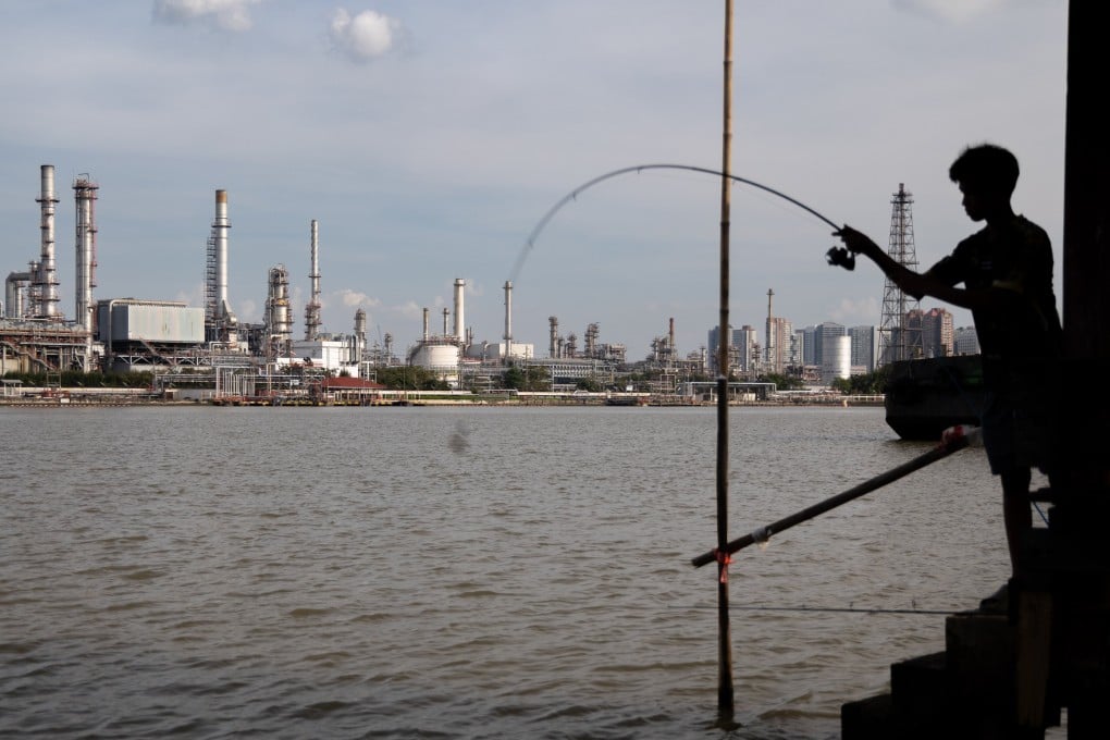 A boy fishes in front of an oil refinery in Bangkok, Thailand, earlier this year. Photo: AP