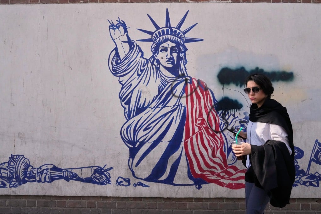 A woman walks past an anti-American mural on the wall of the former US Embassy, now a museum, in Tehran. Photo: AP