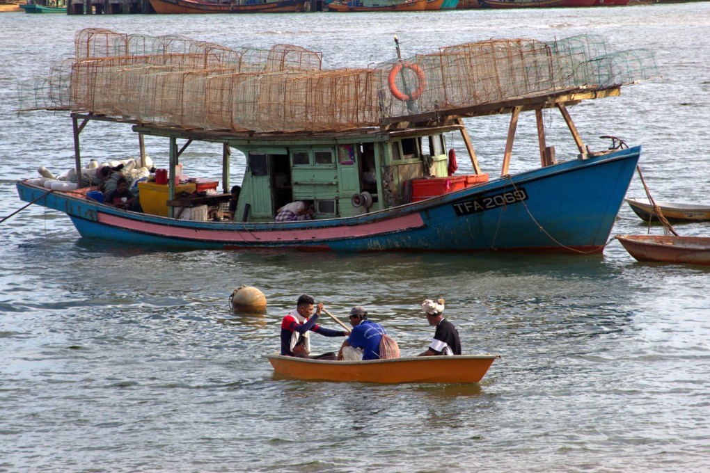 Men row a sampan in front of a local fishing boat in Terengganu, Malaysia. Photo: Keith Mundy