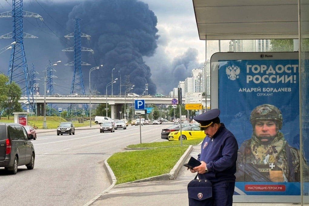 Muscovites go about their daily life as black smoke rises from an oil refinery following a Ukranian drone attack on Thursday. Photo: AFP