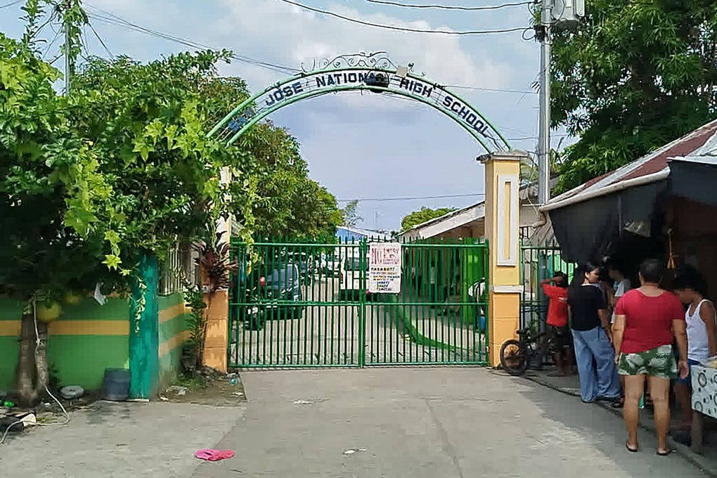 People stand next to the entrance gate of San Jose National High School after a shooting incident in Tacloban City, Leyte province, the Philippines, on Monday. Photo: AFP