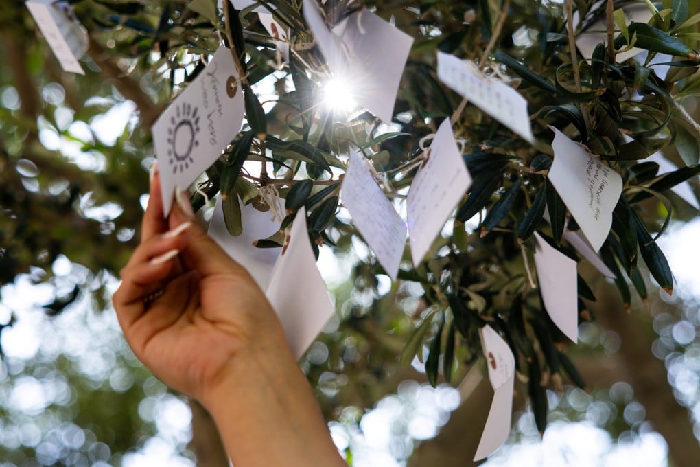 A visitor ties a paper tag bearing a wish onto a tree in the courtyard of The Broad in Los Angeles, California, part of Yoko Ono’s Wish Trees for Los Angeles installation. Photo: TNS