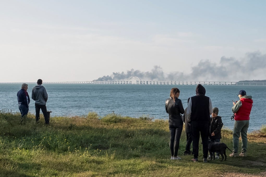 People watch fuel tanks ablaze and damaged sections of the Kerch bridge in the Kerch Strait in Crimea in 2022. Photo: Reuters