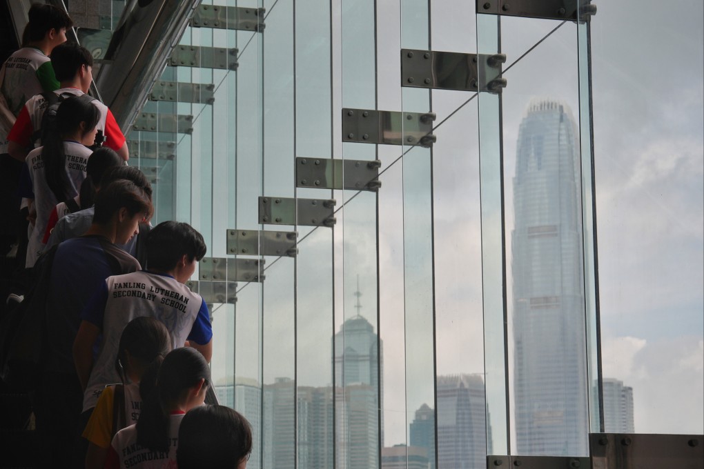 Students look out at the Hong Kong skyline while riding an escalator in Wan Chai. Photo: Elson Li