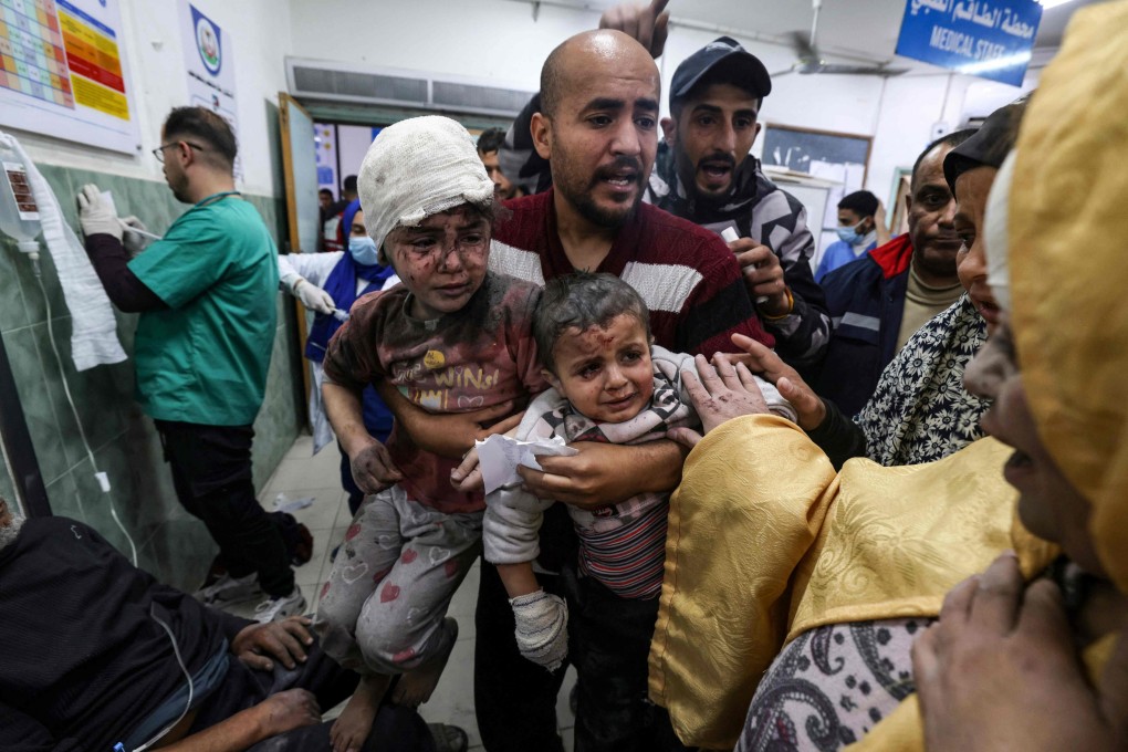 A man in a Gaza Strip hospital in March 2024 carries two children injured during an Israeli bombardment. Photo: AFP