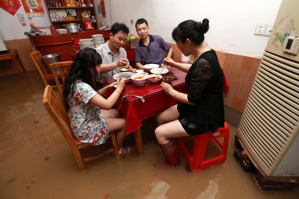 A family carries on eating during a flood in Liling, Hunan province. Photo: AFP