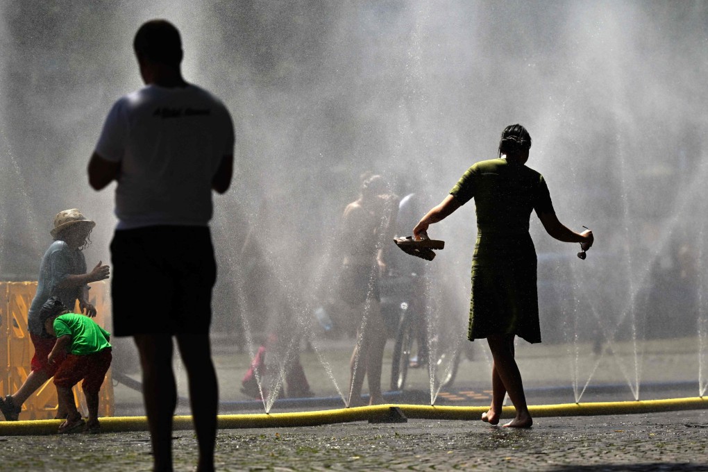 People cool down near water misters in Cologne, Germany, on Thursday. Photo: AFP
