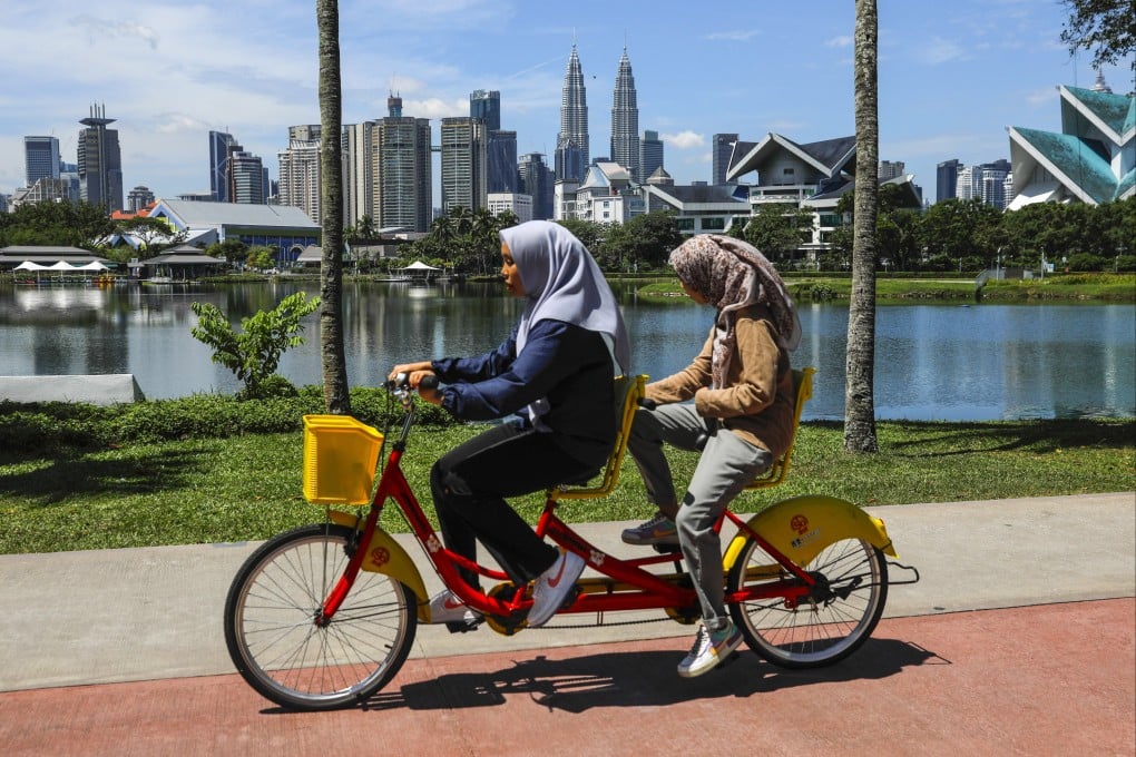 Women ride a tandem bicycle at a lake near the capital city in Kuala Lumpur, Malaysia. Photo: EPA-EFE