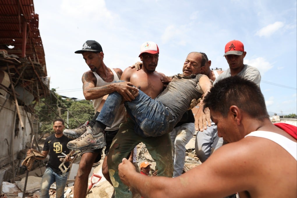 Neighbours carry a man rescued from the rubble of a collapsed building in La Guaira, Venezuela, on Thursday. Photo: AP