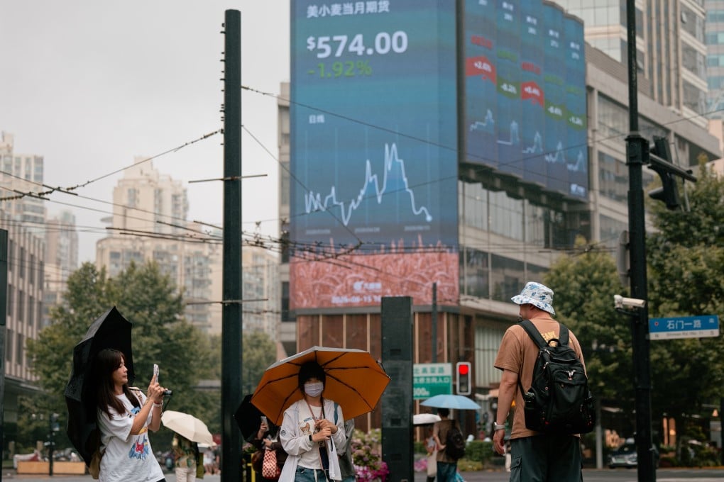 People take pictures beneath a screen showing stock data in Shanghai on June 15. Photo: EPA