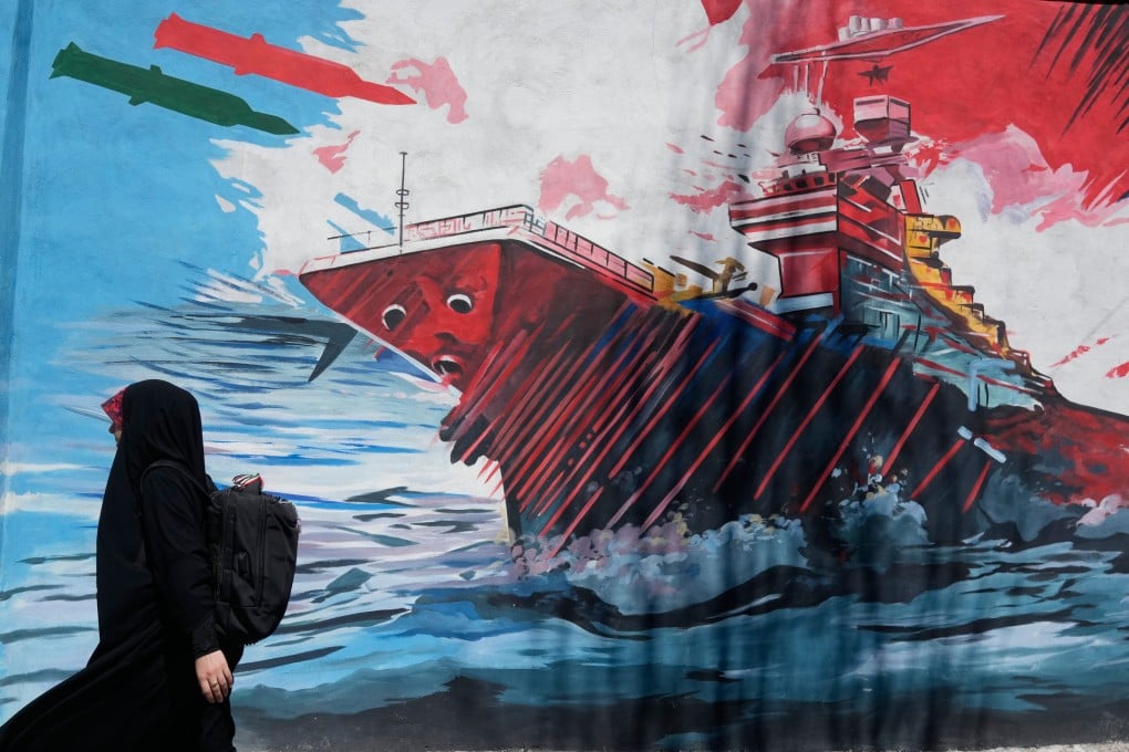 A woman walks past a mural depicting a US aircraft carrier under missile attack in downtown Tehran, Iran, on June 8. Photo: AP