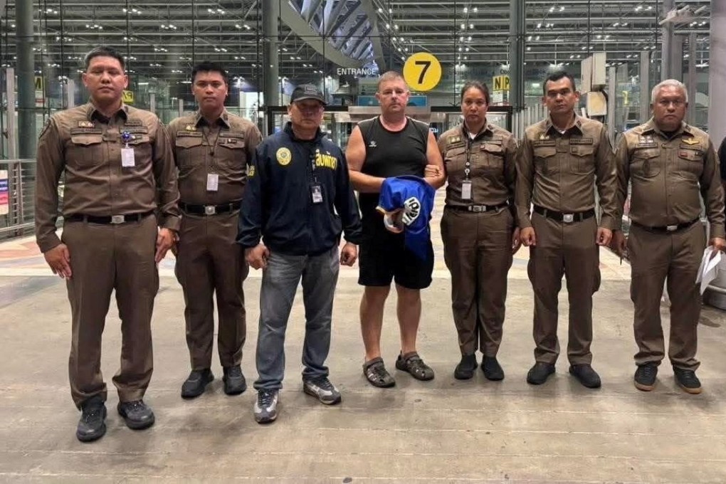 Police officers pose with Carman Simon Peter, an Australian man arrested in the suspected murder of a 17-year-old Thai girl in Pattaya, at Suvarnabhumi International Airport, Thailand on Saturday.   Pattaya Provincial Photo: Police via Reuters