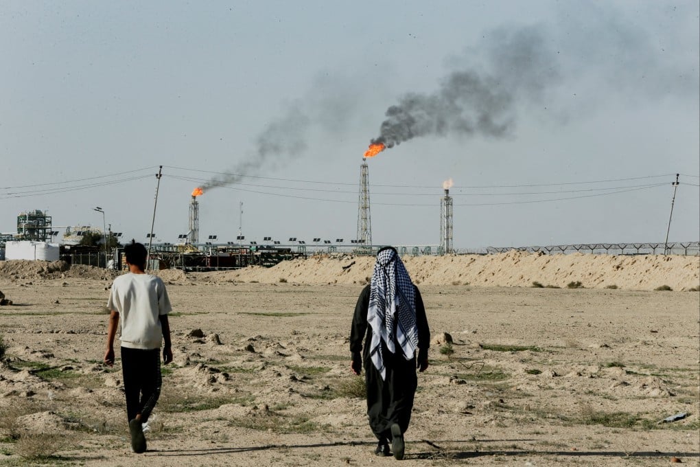 People walk near an oil field near Basra, Iraq, in March. Photo: Reuters