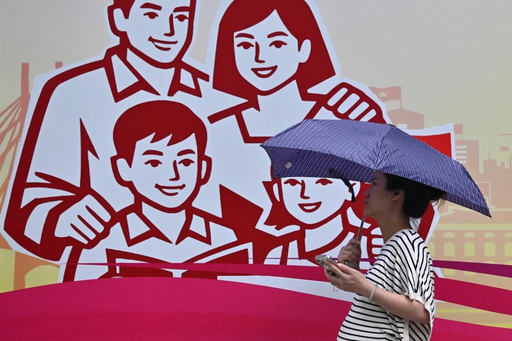 A pregnant woman walks past a billboard of a happy family in Hanoi on  Monday. Photo: AFP
